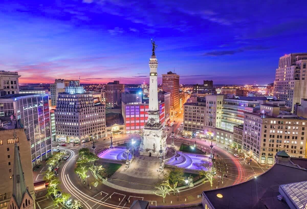 A cityscape at dusk with a prominent tower and illuminated buildings.