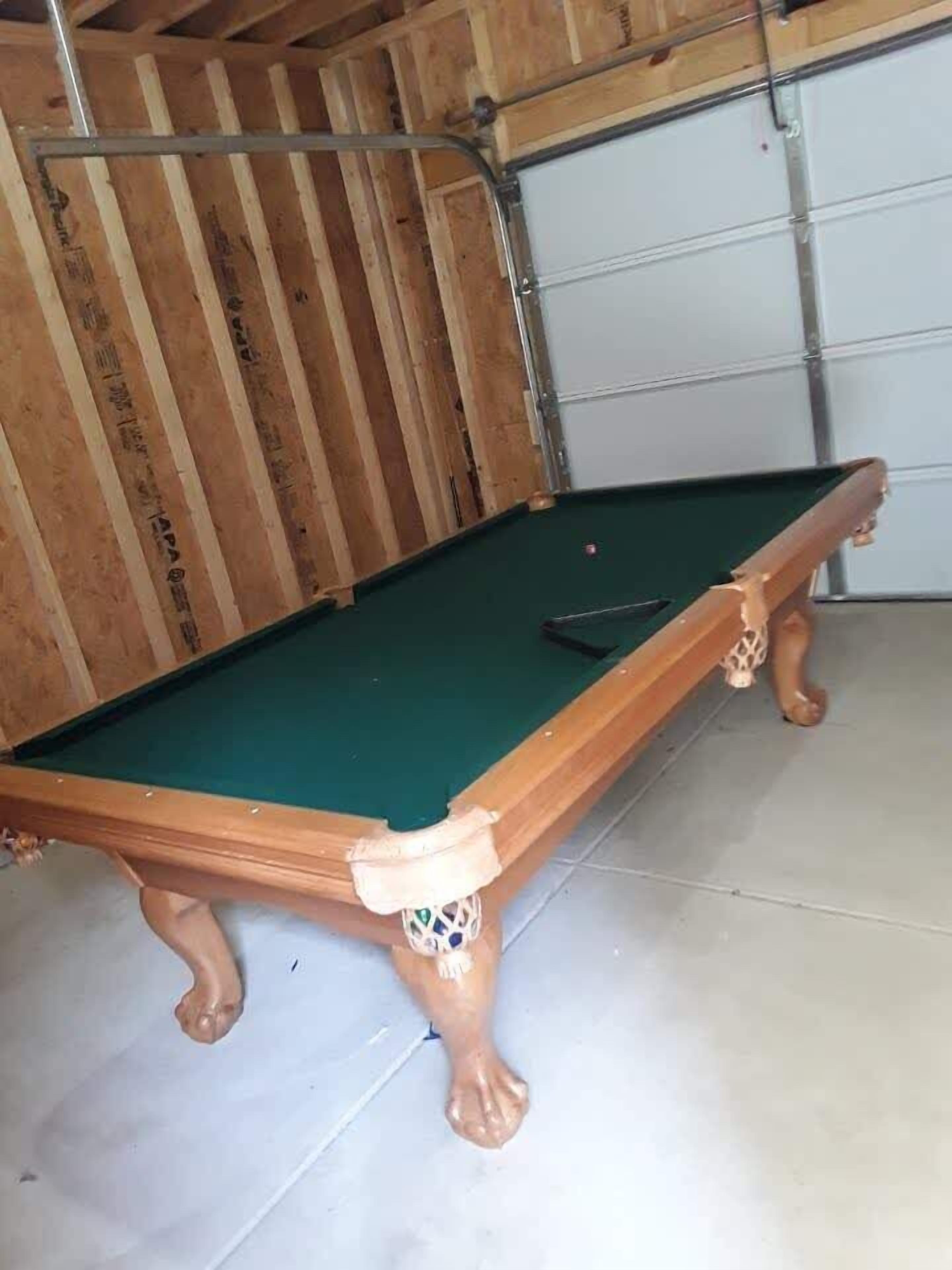 Un tavolo da biliardo in una stanza con pareti in legno e un'ampia porta garage sullo sfondo.
