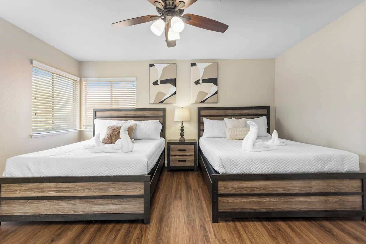 Une chambre d’hôtel avec deux lits, un ventilateur de plafond et des œuvres d’art accrochées au mur.
