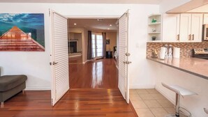 A modern kitchen with white cabinets, a stainless steel refrigerator, and a bar area with a high stool. - Rare 4BR Beauty with Pool 7 min to Strip! (Las Vegas)