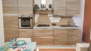 A modern kitchen with wooden cabinets, a built-in oven, a gas stove, and a sink. - Casa Chiara in centro con corte privata (San Benedetto del Tronto)