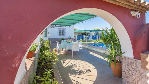 Ein Außenbereich mit Terrasse, Pool, Tisch mit Stühlen und Topfpflanzen.