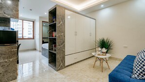Una sala de estar moderna con un sofá azul, una chimenea de mármol, un armario blanco y una pequeña mesa con una planta.