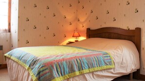 A bedroom with a wooden headboard, a bed with a colorful blanket, a bedside lamp, and patterned wallpaper. - House in Dordogne Valley, pets allowed (Cénac-et-Saint-Julien)