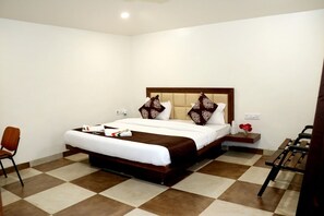 A hotel room with a large bed, a bedside table, a chair, and a bench. - Moustache Panarpani Retreat (Pipariya)