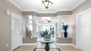 A hallway with a glass-top table, white doors, and a ceiling fan.