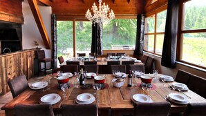 A wooden dining room with a large table set for a meal, surrounded by chairs.
