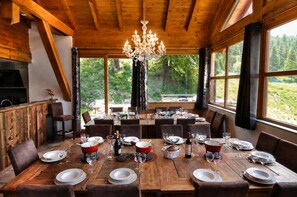 A wooden dining room with a chandelier, large windows, and a view of the outdoors.