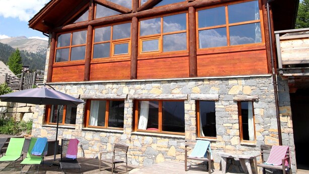 A two-story log cabin with large windows and a stone facade.