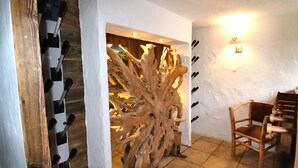 A room with a wine rack, a wooden sculpture, and a chair.