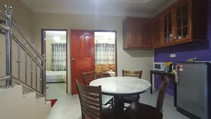 Una cocina compacta con comedor, armarios de madera, un refrigerador y un microondas.