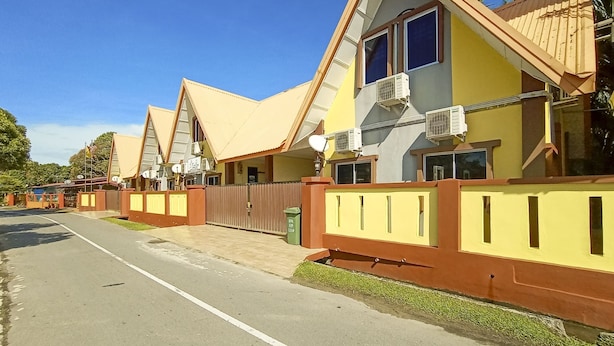 Un conjunto de casas modernas, amarillas y marrones, con entrada protegida por una reja y antenas parabólicas.