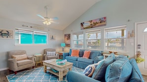 A spacious living room with a large blue couch, a wooden coffee table, and a ceiling fan. - PC635 Close to Beach and Restaurants, Golf Cart Access (Port Aransas)