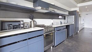 Een moderne keuken met grijze kastjes, een inbouwoven, een magnetron en een gasfornuis.