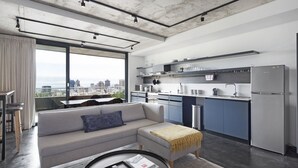 Een modern appartement met een zithoek, keuken en grote ramen met uitzicht over de stad.