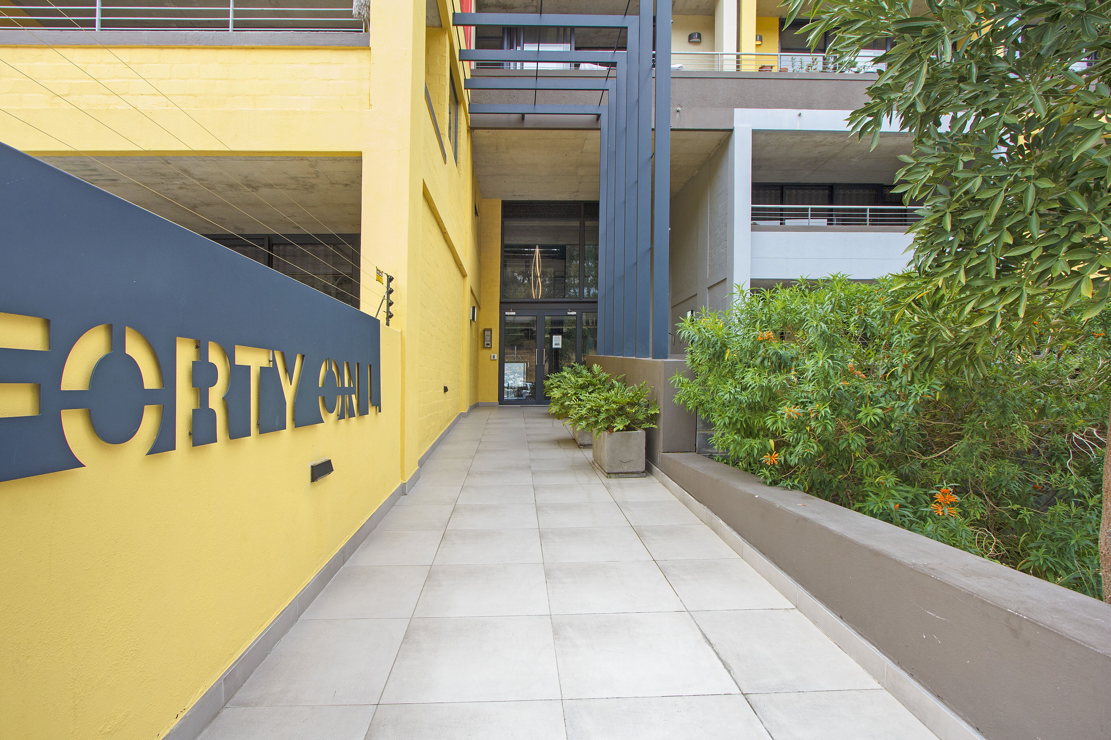 A building entrance with a yellow wall and a sign that reads "FORTY".