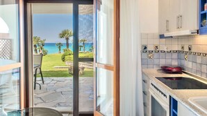 A kitchen with a view of the ocean, a stone patio, and a dining area with a table and chairs. - Seafront Paradise Home (Skala Fourkas, Halkidiki)