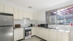 A modern kitchen with white cabinets, stainless steel appliances, and a large window providing natural light.