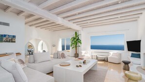 Un salon moderne avec un canapé blanc, une table basse et une grande fenêtre donnant sur la mer.