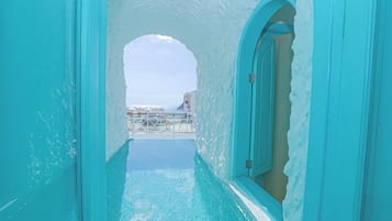 A turquoise infinity pool with a view of the sea and a building in the background.