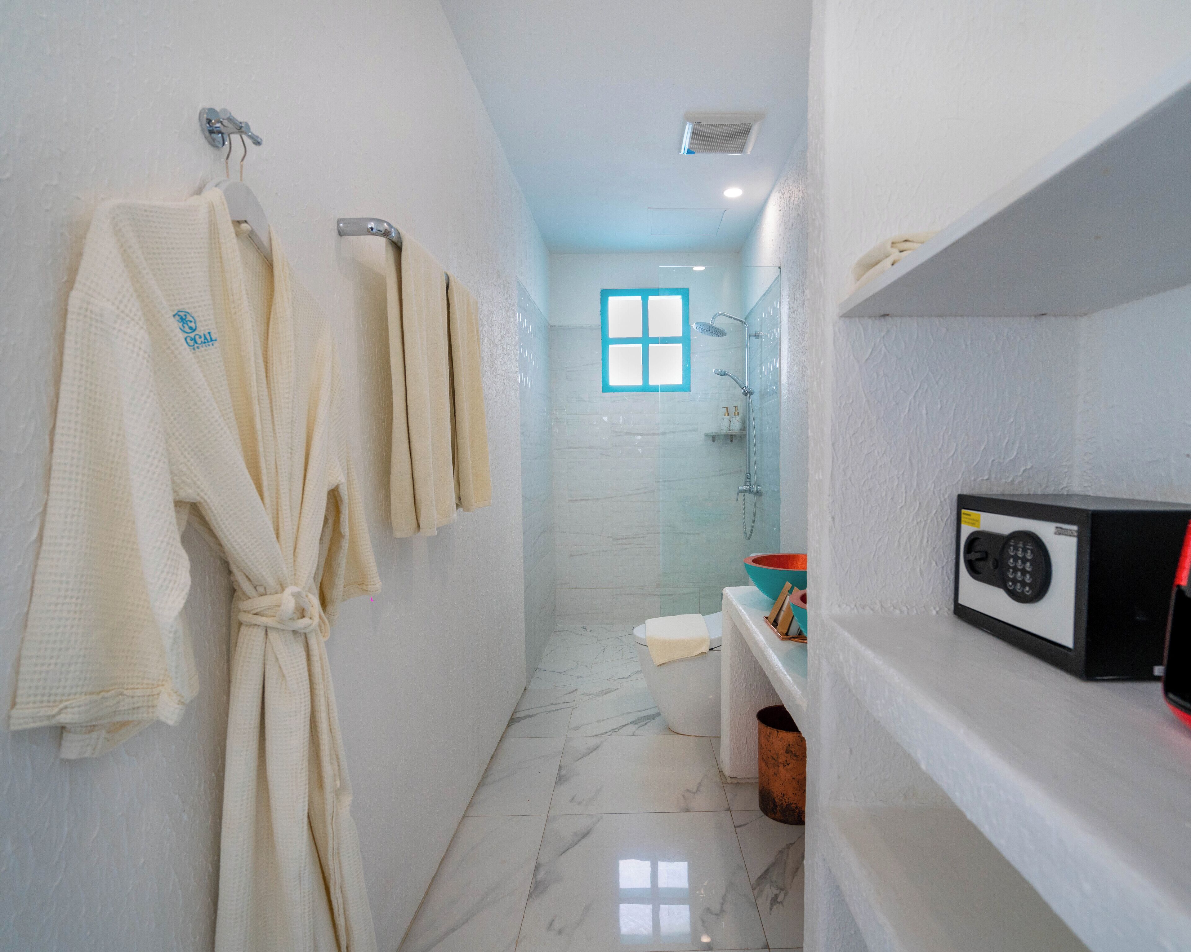 A bathroom with a white marble floor, a shower, a toilet, and a microwave on a shelf.