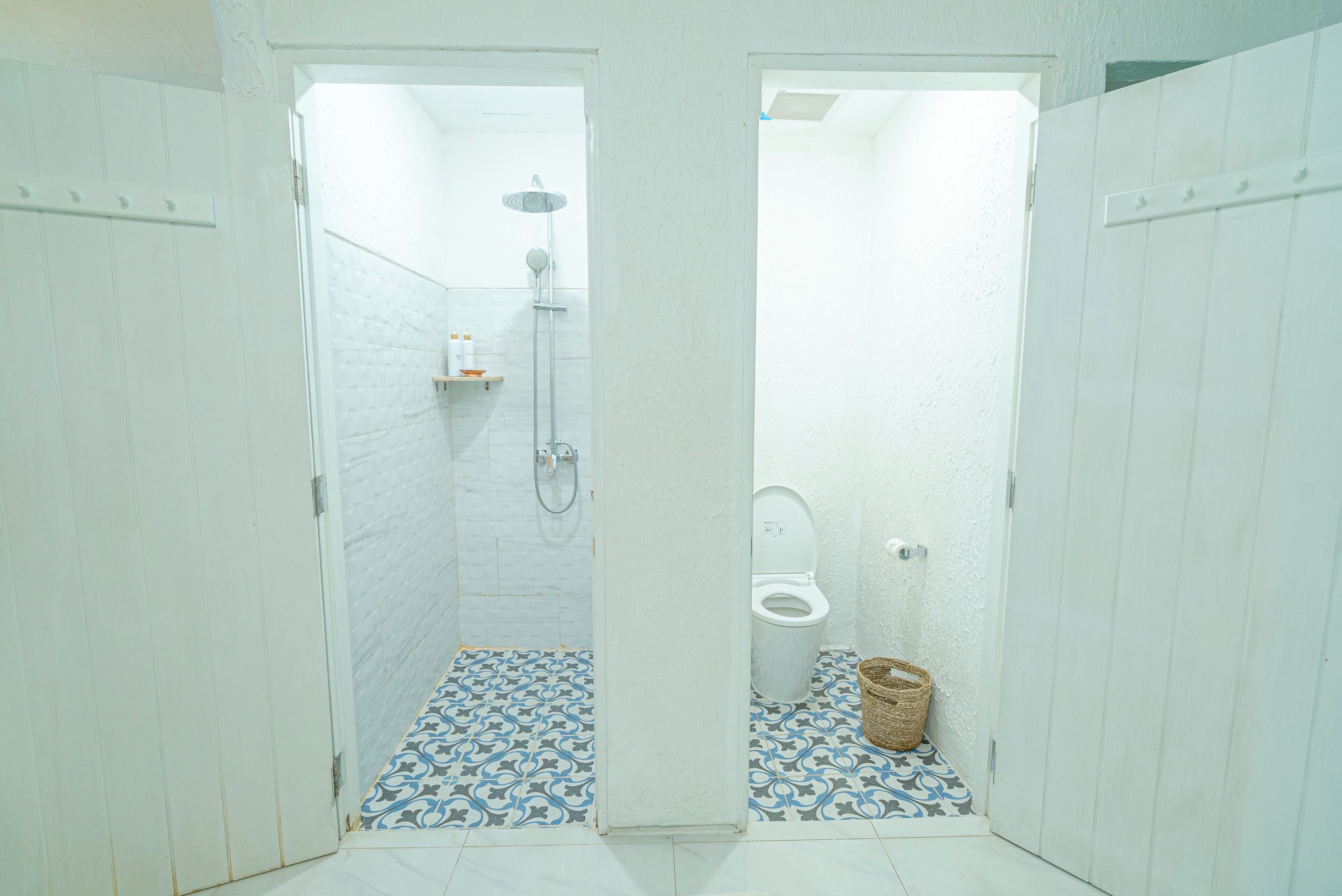 A small, narrow bathroom with a shower, toilet, and a patterned floor.