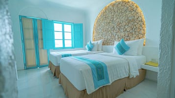 A hotel room with two beds, a stone wall headboard, a window with blue shutters, and a white tiled floor.