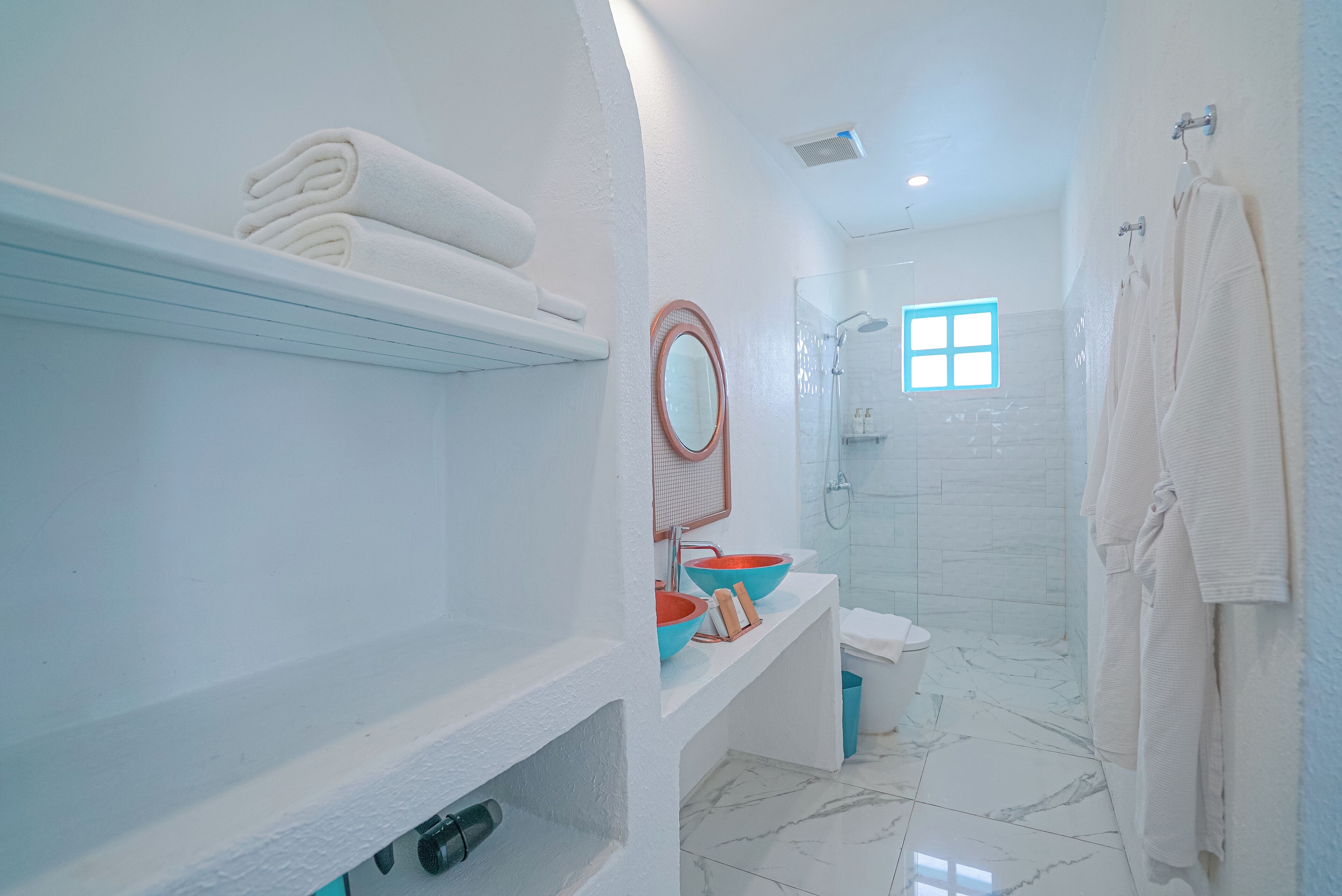 A modern bathroom with a white sink, a mirror, and a shower area.