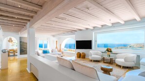 Amplia sala de estar con un ventanal que ofrece vista al mar, una chimenea moderna y un rincón de estar acogedor.