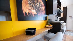 A modern kitchen with a microwave, oven, and sink. There is a wooden counter with a black tray and a bowl of fruit. - Appartamento Francesca (Sirmione)