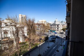 A city street with historic buildings, a clear sky, and a view of a tall building in the distance.