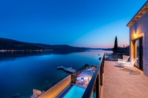 A balcony with a pool, overlooking a calm lake at dusk. - Luxury Villa Sol del Mar II - Adriatic Gem  (Slano)