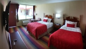 A hotel room with two beds, a TV, a small table, and a window with curtains. - Ramada Perry near Fairgrounds (Perry)