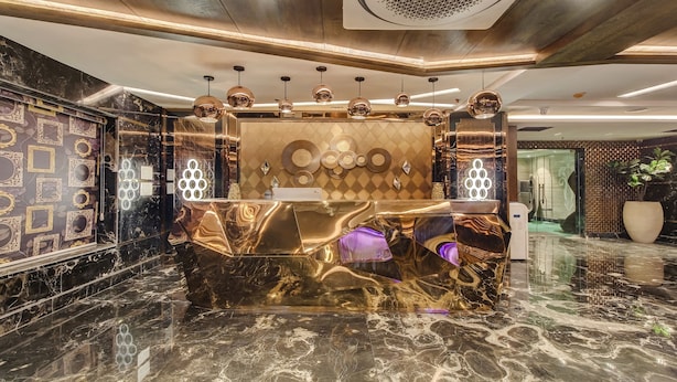 A luxurious lobby with a marble reception desk, pendant lighting, and a decorative wall with framed mirrors. - Treebo Premium Tahoora International (Kolkata)