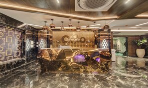 A luxurious lobby with a marble reception desk, pendant lighting, and a decorative wall with framed mirrors. - Treebo Premium Tahoora International (Kolkata)