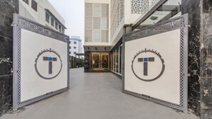 A corridor with a modern design, featuring a central door with a decorative emblem. - Treebo Premium Tahoora International (Kolkata)