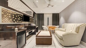 A modern living room with a sofa, coffee table, and a TV mounted on the wall. - Treebo Premium Tahoora International (Kolkata)