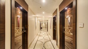 A hotel corridor with wooden doors numbered 407 and 409, a marble floor, and recessed lighting. - Treebo Premium Tahoora International (Kolkata)