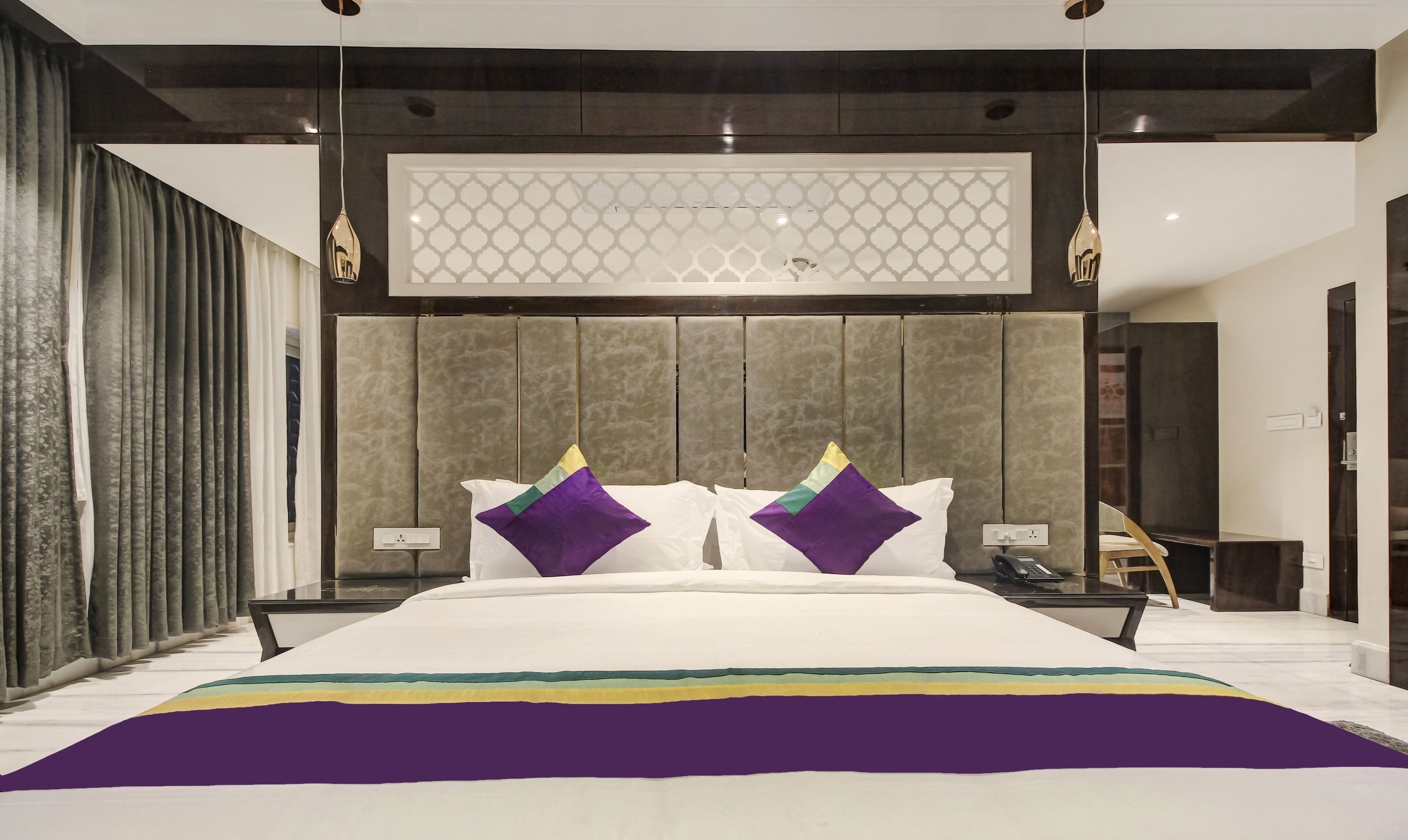 Un dormitorio moderno con una cama grande, un cabecero decorativo y una mesita de noche con lámpara.