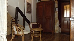 Une pièce avec un escalier, une armoire en bois et des chaises en osier.