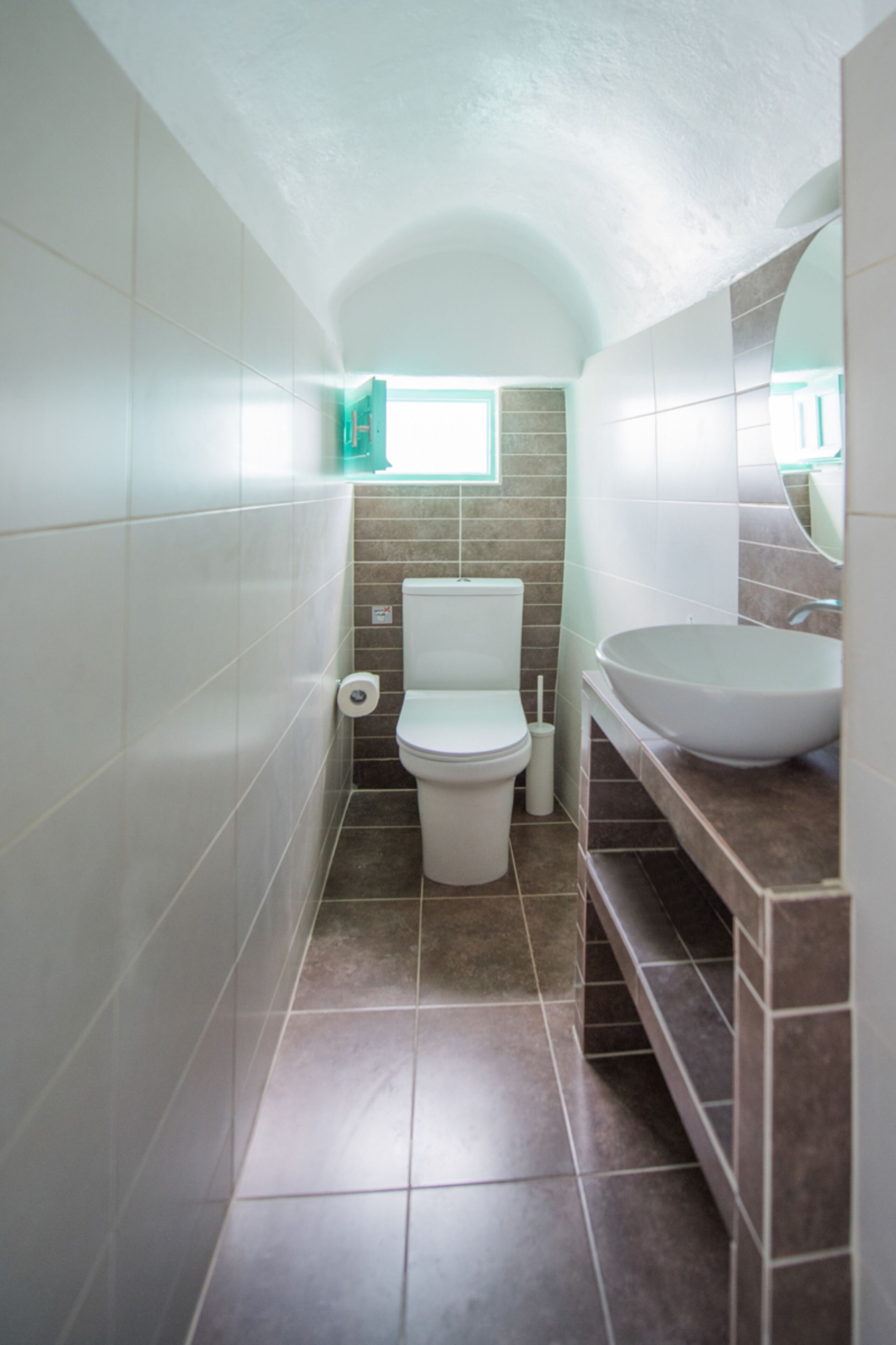 A compact bathroom with a toilet, a sink, and a window.