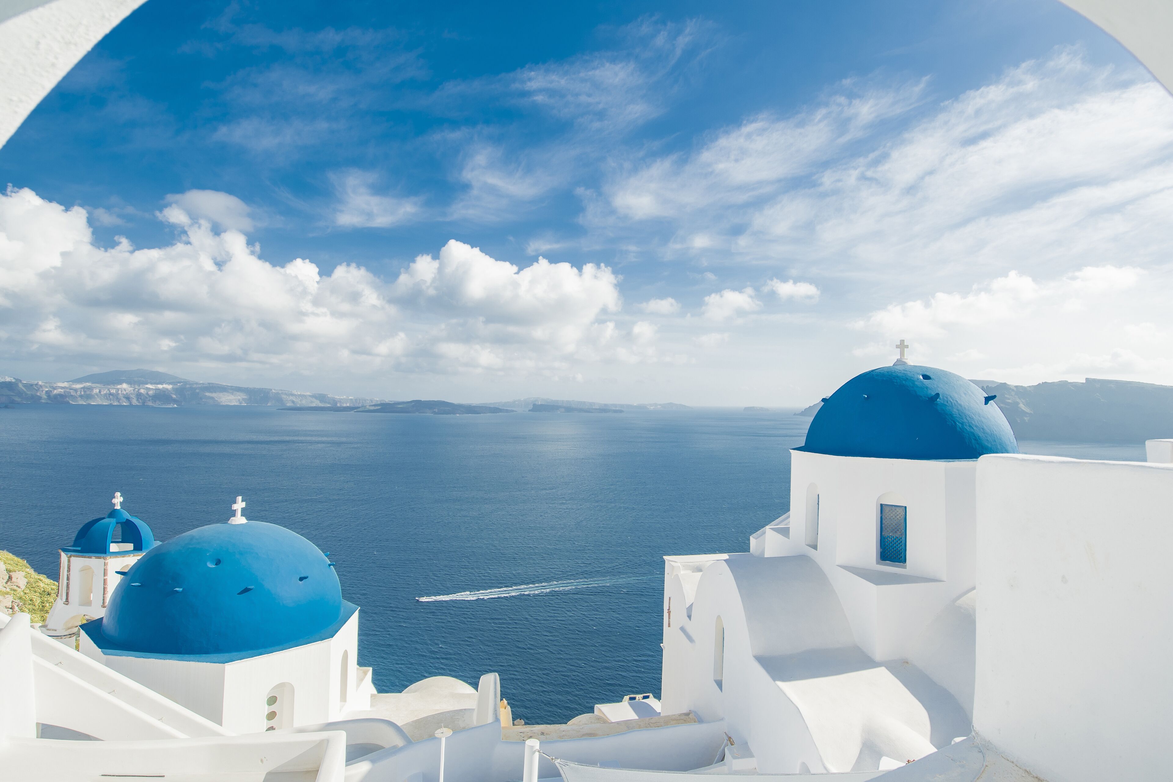 A coastal view with white buildings and blue domes, overlooking the sea.