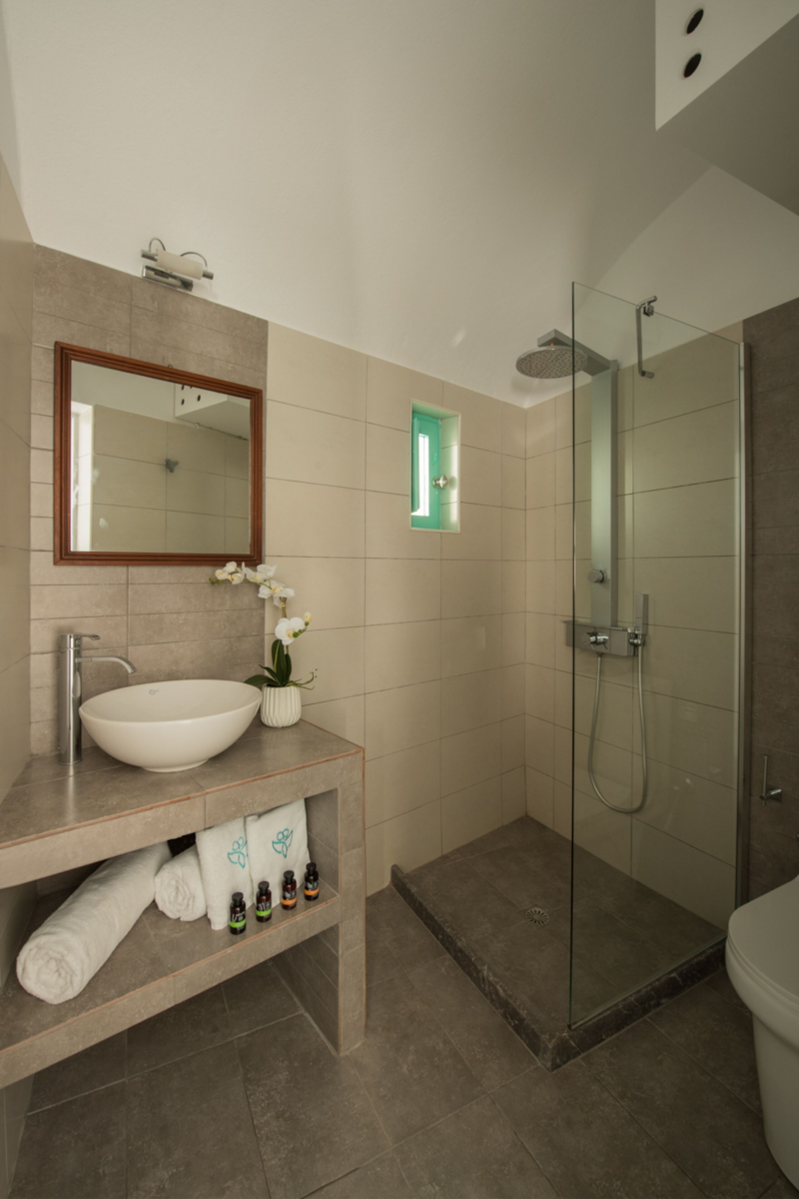 A bathroom with a white sink, a mirror, a shower, and a toilet.