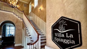 Eine prachtvolle Treppe mit einer Chandelüster, einem Schild mit der Aufschrift "Villa La Spiaggia" und Blick ins Innere.