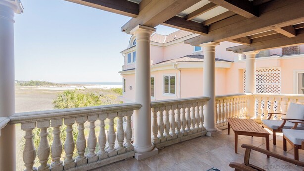 Ein Balkon mit Blick auf den Strand, Holzmöbel und ein Fliesenboden.