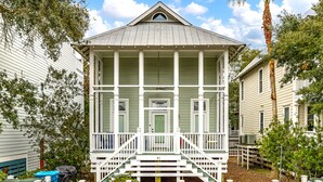 Une maison à deux étages avec un porche, un escalier d’entrée et une enseigne indiquant qu’il s’agit d’une location de vacances.