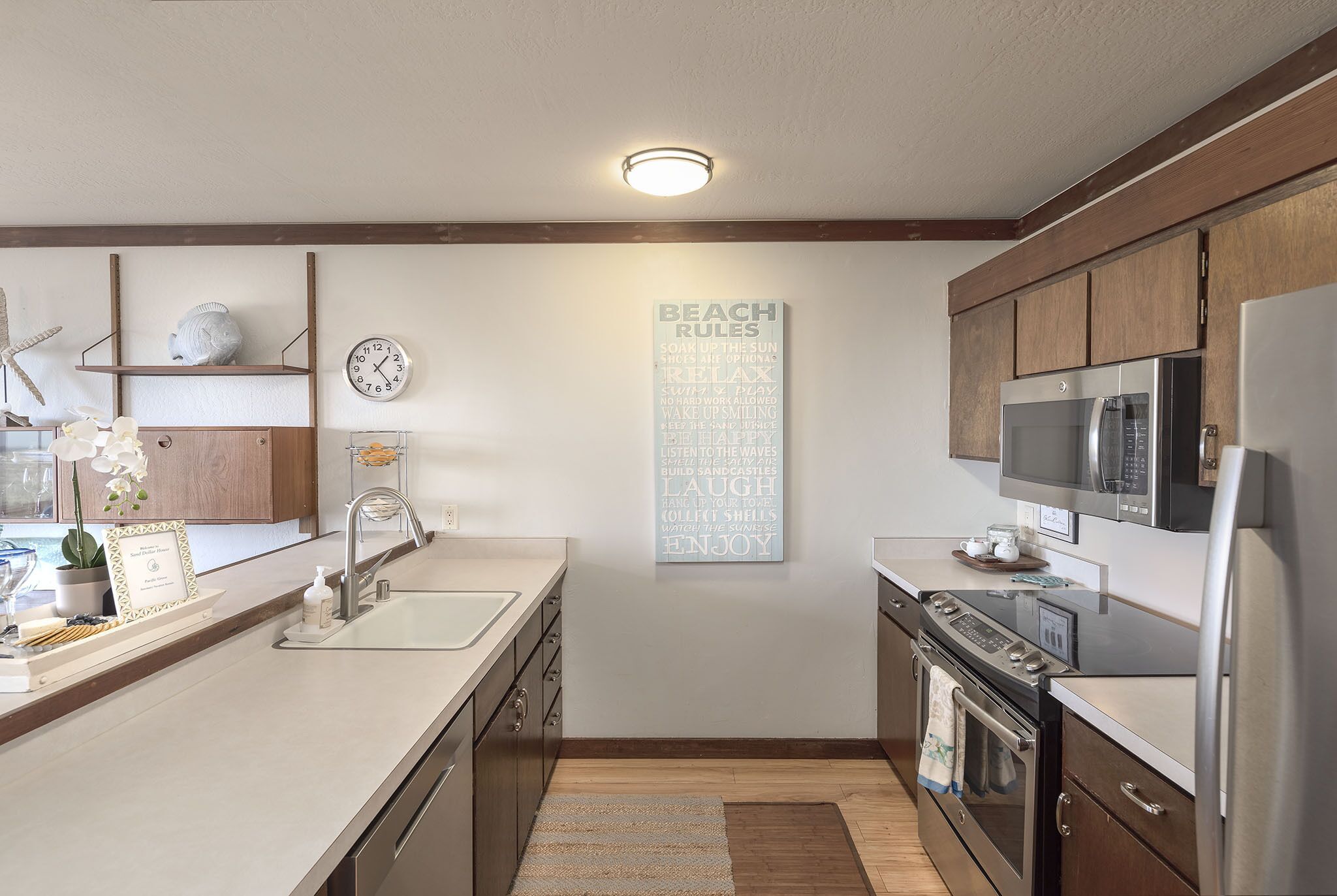 A kitchen with wooden cabinets, a stainless steel refrigerator, a microwave, and a sink.