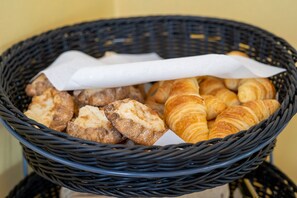 Un panier contenant divers produits de boulangerie, notamment des croissants et des pâtisseries.
