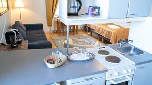 A compact kitchenette with a refrigerator, stove, sink, and a small countertop. - Boutique Hotel Willa Aria (Savonlinna)