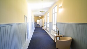 A hallway with a blue carpet, white walls, and a beige armchair. - Boutique Hotel Willa Aria (Savonlinna)